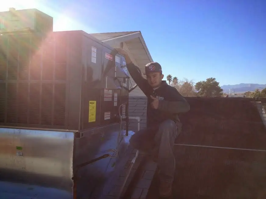 HVAC technician performing Air Duct Cleaning on a rooftop unit in Ives Estates